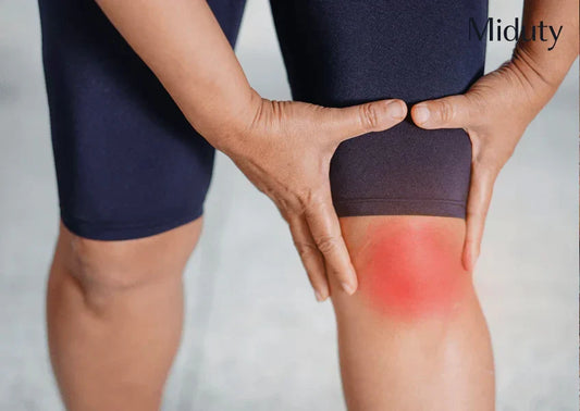 Person holding their knee with redness indicating discomfort or pain.