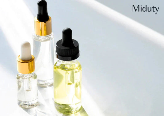 Three dropper bottles with various contents on a reflective surface.