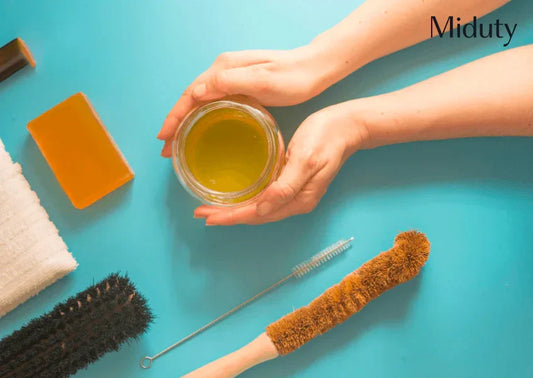 Hands holding a jar of homemade cleaner with cleaning tools on a blue background