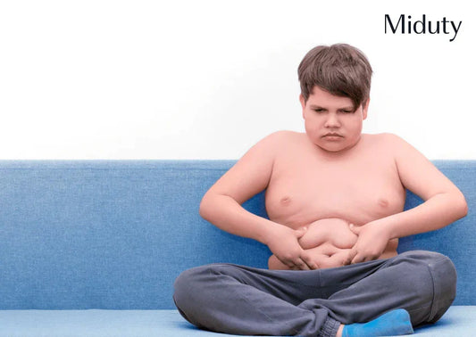 Boy sitting on a couch, holding his stomach, looking concerned about his weight.